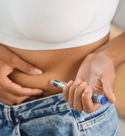 Eine Frau setzt sich eine Abnehmspritze in den Bauch.